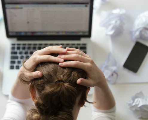 A thoughtful woman sitting at her desk, looking concerned and reflective, symbolising the impact of toxic positivity in the workplace.