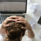 A thoughtful woman sitting at her desk, looking concerned and reflective, symbolising the impact of toxic positivity in the workplace.