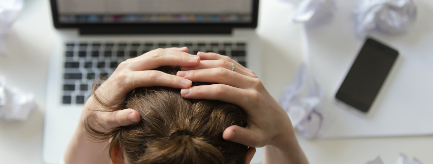 A thoughtful woman sitting at her desk, looking concerned and reflective, symbolising the impact of toxic positivity in the workplace.